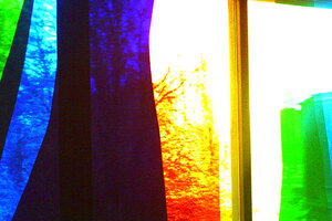 Färgad glasruta med ljusinsläpp som lyser upp färgerna blått, rött och gult.
