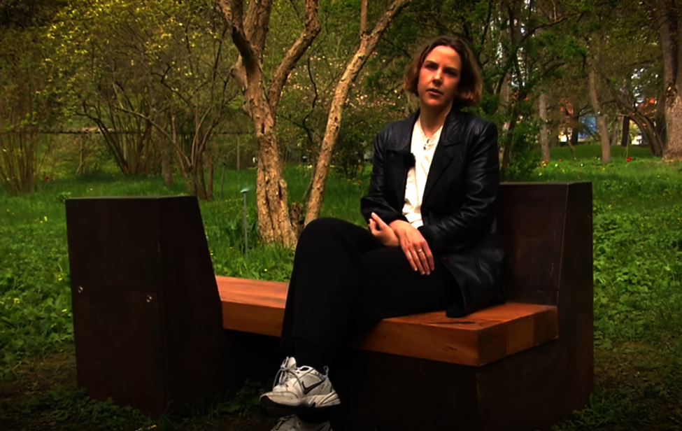Konstnären Jonna Hägg sittande på ljudbänken i Botaniska trädgården. Foto: Karsten Runderheim