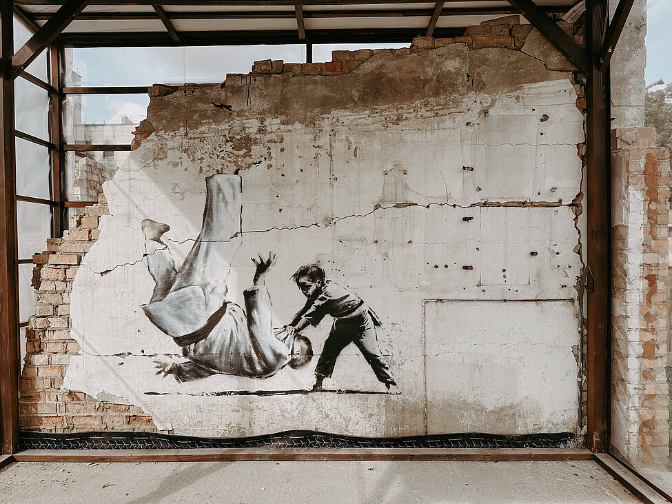 Banksy grafitti med liten judokille som kastar ner en större judokille.