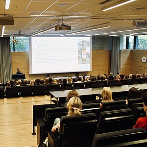 Studenter i sal lyssnar till en presentation. Foto.