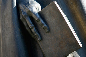 Staty föreställande en person som håller i en bok.