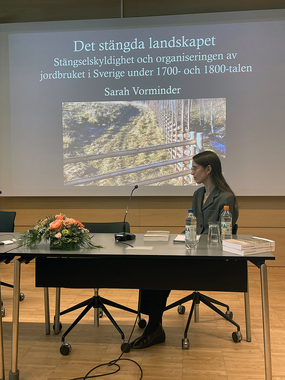 Sarah sitter vid en kateder vid disputationen. Foto.