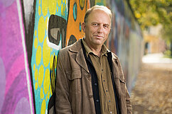 Erik Magntorn står framför en graffitimålad mur.