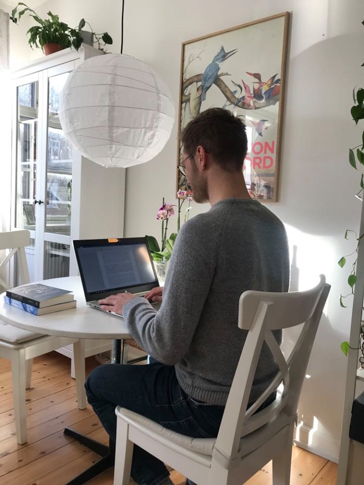 En person sitter vid ett bord med en bärbar dator framför sig.