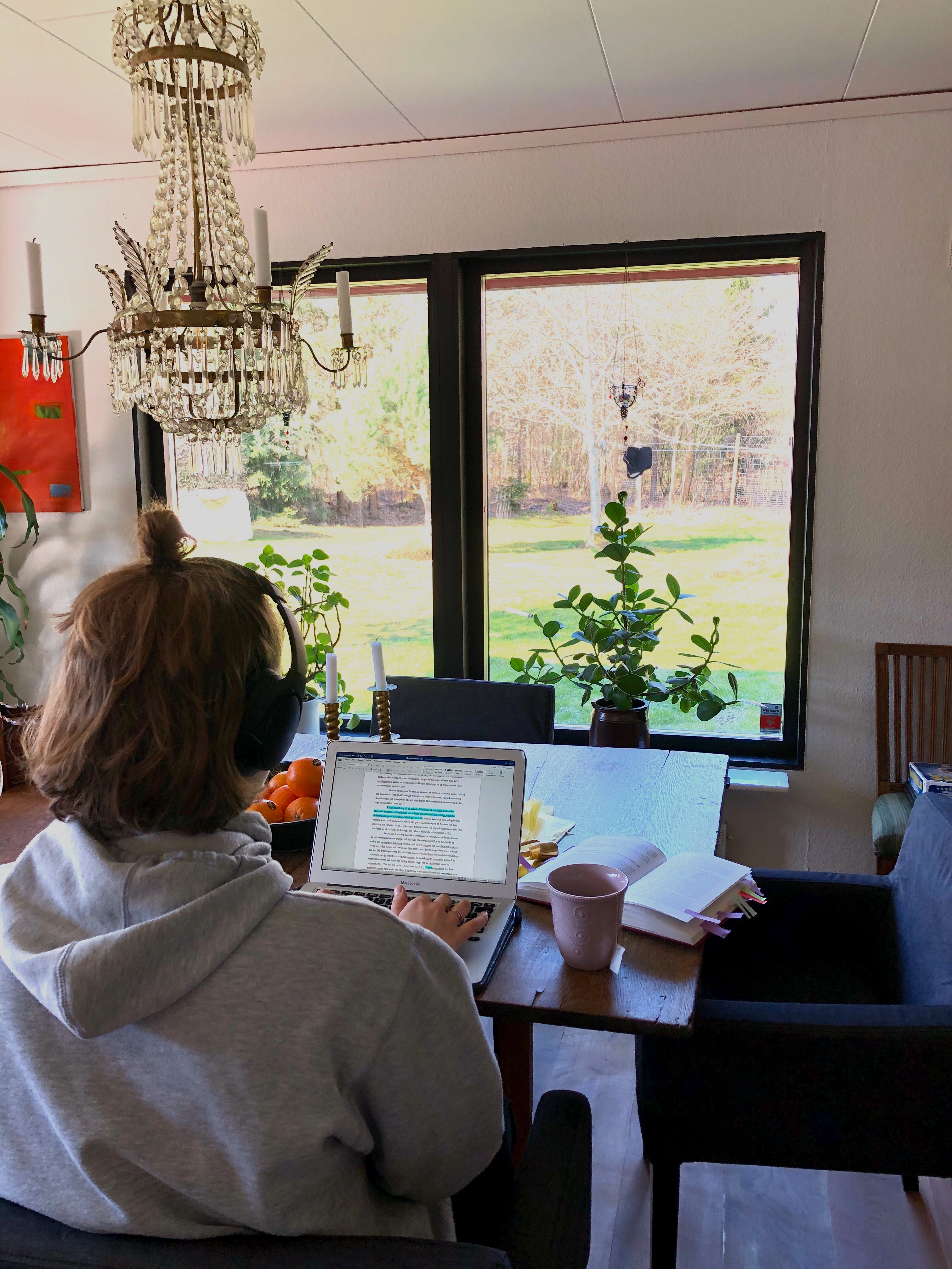 Student sitter och arbetar med bärbar dator vid bord i ett vardagsrum.